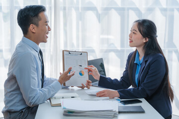 Asian business team discussing over laptop in a corporate. Group collaboration and teamwork concept.
