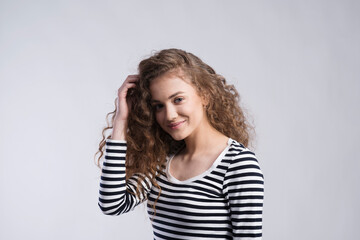 Portrait of a gorgeous teenage girl with curly hair. Studio shot, white background with copy space