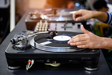 Obraz premium Close up hands of a dj playing Disc jockey scratches records on turntablebs in live music concert at night club.