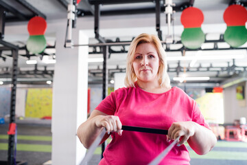 Portrait of overweight woman exercising in gym.