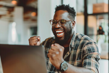 Happy man celebrating in front of a laptop in the office