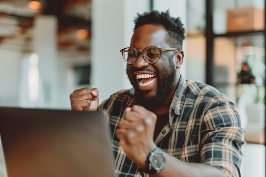 Happy man celebrating in front of a laptop in the office