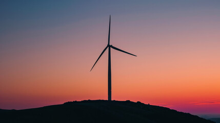A wind turbine is standing on a hill in front of a beautiful sunset