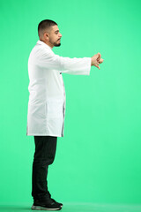 The doctor, in full height, on a green background, shows his thumbs down