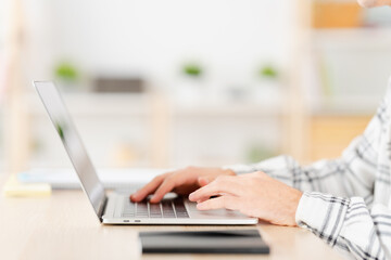 Close-up photo of a hands of a man using laptop sitting at home and working