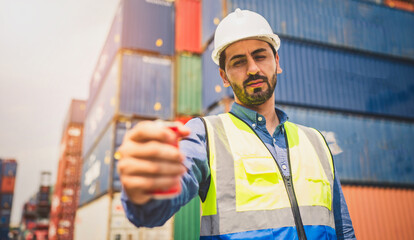 Portrait of Engineer or foreman wears PPE checking container storage with cargo container...