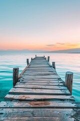 Fototapeta premium A weathered wooden pier extending into turquoise waters, disappearing into the hazy sunset