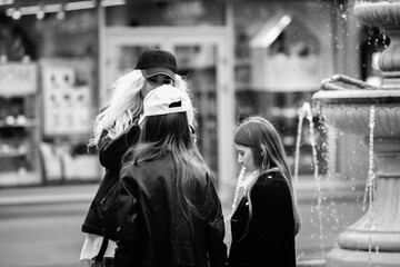 Portrait of a young beautiful mother and two daughters in a summer city.