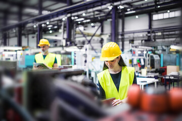 Warehouse employees in warehouse. Two workers in reflective clothing in modern industrial factory,...