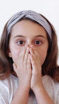 Vertical video. Scared child. Kid fear. Frightened afraid little girl covering face with hands showing oh no omg reaction isolated on white background.