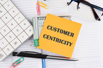Customer Centricity word written on a yellow sticker with money on a business notebook