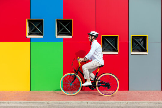 Man cycling by vibrant geometric wall