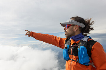 A man in an orange jacket pointing to the sky