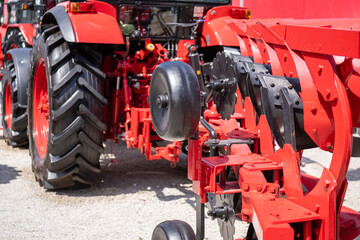 Red tractor with plow on a agricultural field.