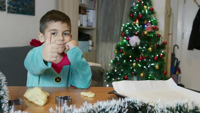 Cute child dressed in elf costume making gingerbread cookies. High quality 4k footage