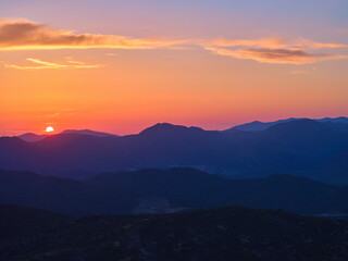 Fototapeta premium Stunning sunset over mountain ridges with vibrant orange and purple hues, capturing the beauty of dusk in a serene Sithonia landscape. Perfect for nature and landscape photography themes.