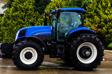 The new blue agricultural tractors of various models stand in a row at the exhibition site in...