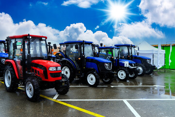 The new blue agricultural tractors of various models stand in a row at the exhibition site in...