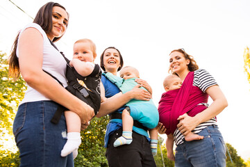 Mothers carrying babies in carriers, slings or wraps. Babywearing.
