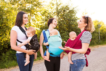 Mothers carrying babies in carriers, slings or wraps. Babywearing.