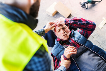 Colleague calling ambulance and giving first aid to injured worker, in pain after accident at...