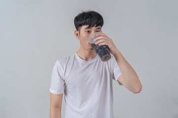 Handsome young man drinks soda and holding plastic cup and soda bottle.