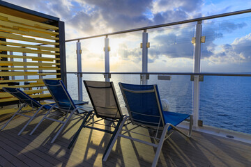 Relaxation on the cruise ship: cloudscape crossed by rays of sun seen from the deck with deckchairs.