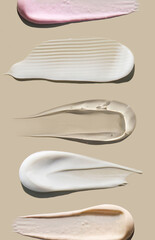 brush strokes of creamy texture of cosmetic samples on a pastel beige background