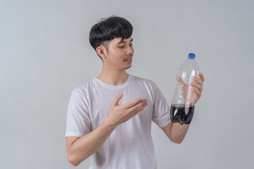 Handsome young man drinks soda and holding plastic cup and soda bottle.