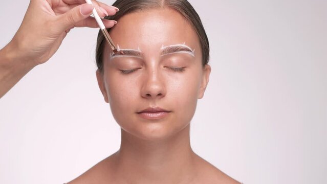 Make-up artist makes markings with white pencil for eyebrow and dyes eyebrows. Professional makeup and facial care.