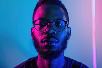 Obraz premium Serious young African American man with glasses smiling on neon background.