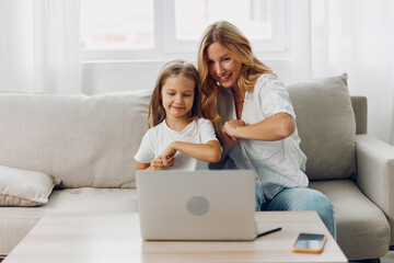 Mother and daughter bonding on the couch while exploring educational content on a laptop together