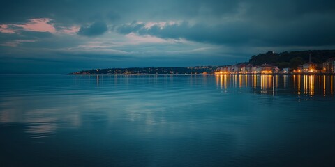 Obraz premium A serene evening scene capturing the tranquility of a coastal town as it is bathed in twilight hues, reflecting on calm waters