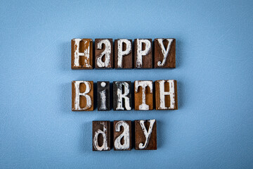 HAPPY BIRTH DAY. Wooden alphabet letter blocks on blue textured background
