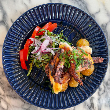 Grilled octobus with potatoes on plate.