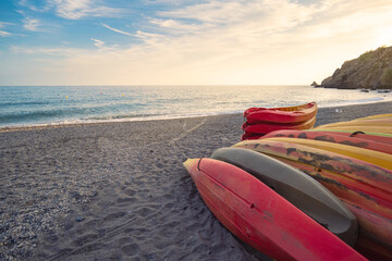 Vertical shot of a beach at sunset with kayaks in the foreground, lifestyle, active tourism