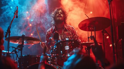 A drummer in action during a concert with dynamic red and blue stage lighting and smoke effects