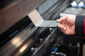 A master bends metal sheets on a machine. Hydraulic Press. 