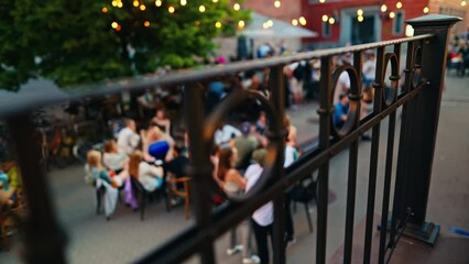 Festive gathering at a cafe outdoors with string lights and fencing in an urban setting