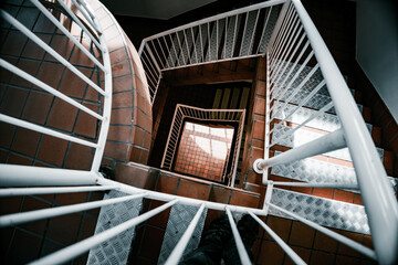 A top-down view of a modern geometric staircase with metal railings and steps, featuring brown and...