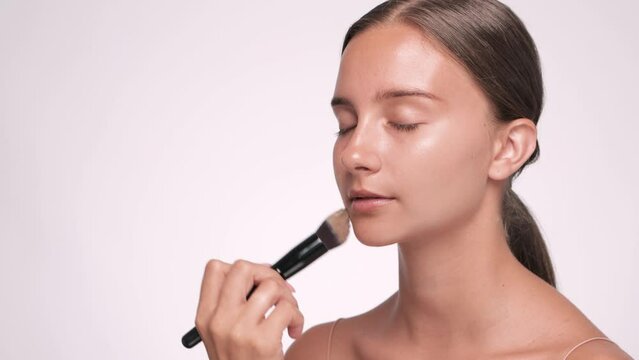 Makeup artist applies foundation on the face of a beautiful girl. Professional makeup concept