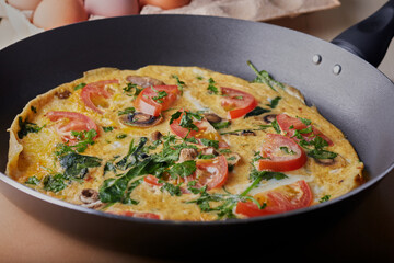 Frying pan with a giant omelette inside ready to eat.
