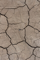 Close-up top view of dry brown cracked clay land surface in a summer day. Abstract weather background. Soft focus. Copy space. Drought and climate change theme.