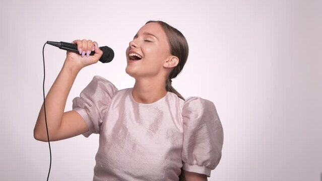 A beautiful joyful girl sings her favorite song into a microphone in a karaoke bar.