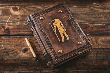 Worn brown leather book with ancient goddess Thoth on the cover.