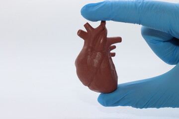 Person wearing gloves holding the 3d printed heart in the fingers with copy space in the left side