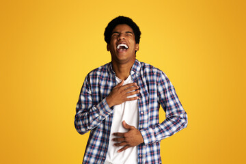 Teenage Guy Laughing Out Loud, Feeling Pain in Belly Muscles from Chuckle, Yellow Background