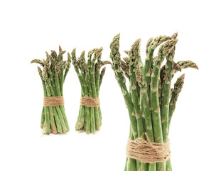 three standing clusters of raw fresh asparagus tied with string