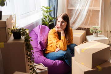 Sad, upset, middle aged woman, packer packing cardboard boxes, sitting at home, looking away