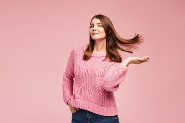 Confident, smiling middle aged woman wearing knitted pink sweater, having beautiful, silky hair